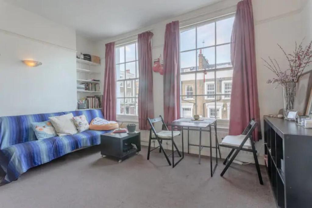 a living room with a blue couch and a table at Lovely Victorian Flat for 6 in Stoke Newington in London