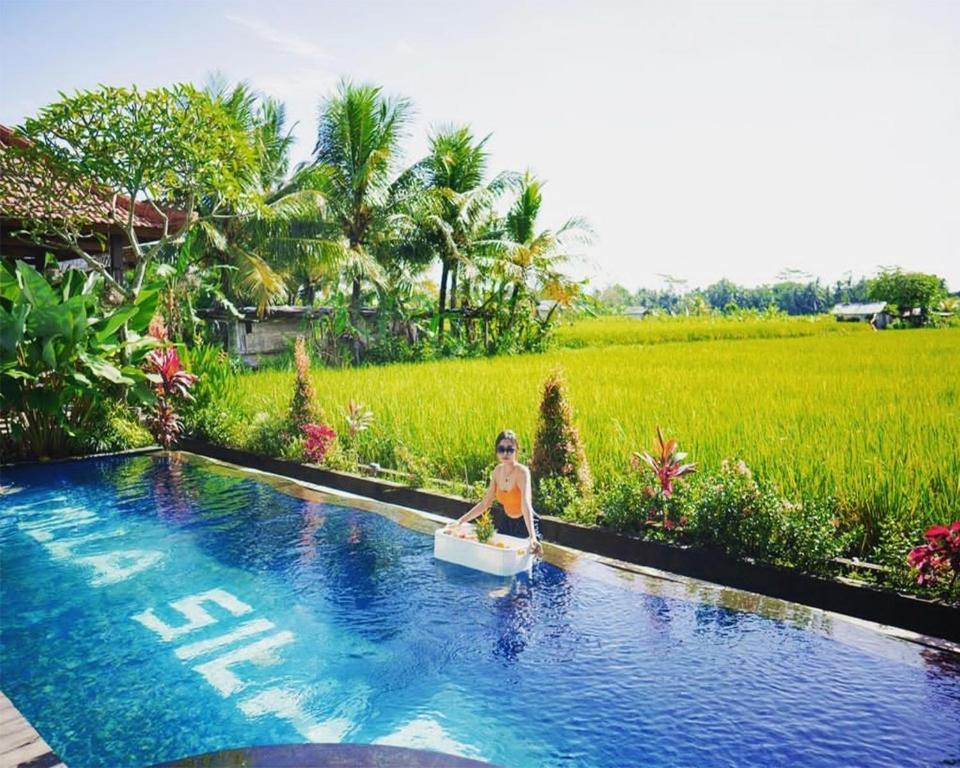 eine Frau, die in einer Badewanne neben einem Pool sitzt in der Unterkunft Villa Silas in Ubud