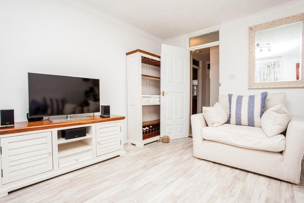 a white living room with a tv and a chair at Modern and Spacious Central 1 Bedroom Apartment with Balcony in London