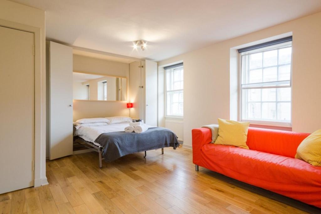 エディンバラにあるModern Studio Apartment on Royal Mile Great for Castleのベッドルーム1室(ベッド1台、赤いソファ付)