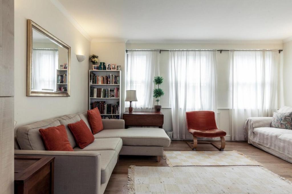 a living room with a couch and a chair at Bright 2 Bedroom Flat in Central London in London