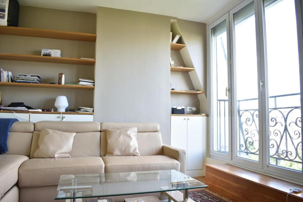 un soggiorno con divano e tavolo in vetro di Fully Renovated Bright Studio With High View a Parigi