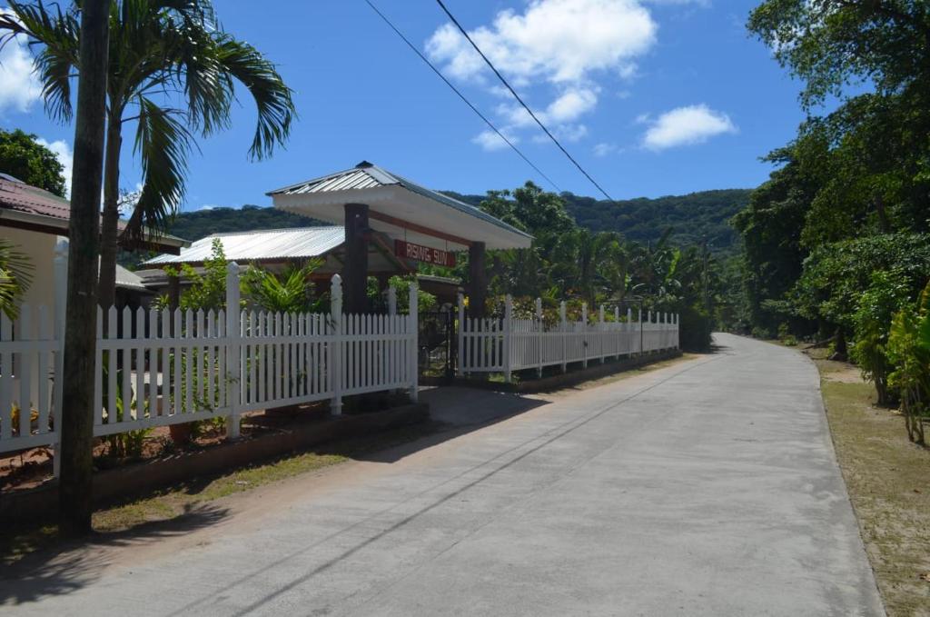 a road leading to a house with a white picket fence at Rising Sun Guesthouse in La Digue