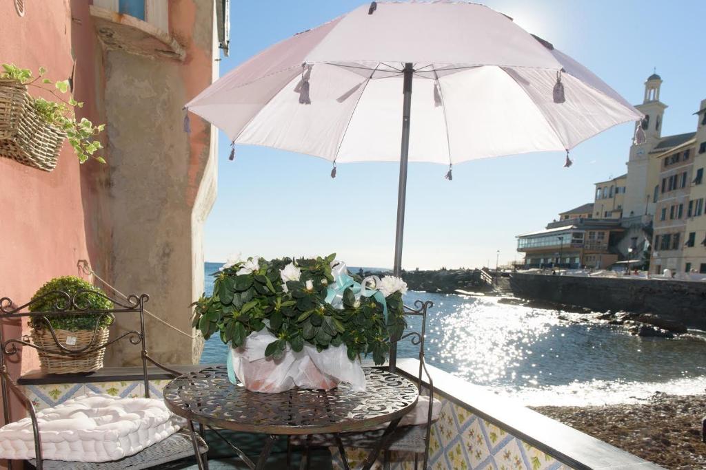 una mesa con sombrilla y flores en el balcón en Salsedine Relais, en Génova