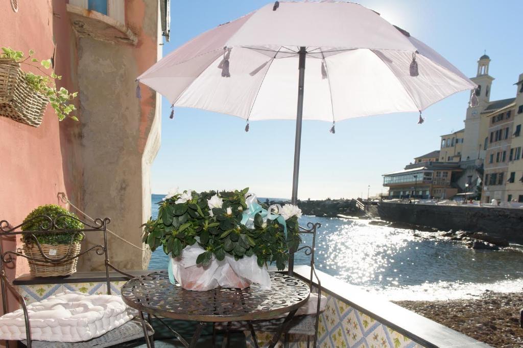 un tavolo con ombrellone e fiori sul balcone di Salsedine Relais a Genova