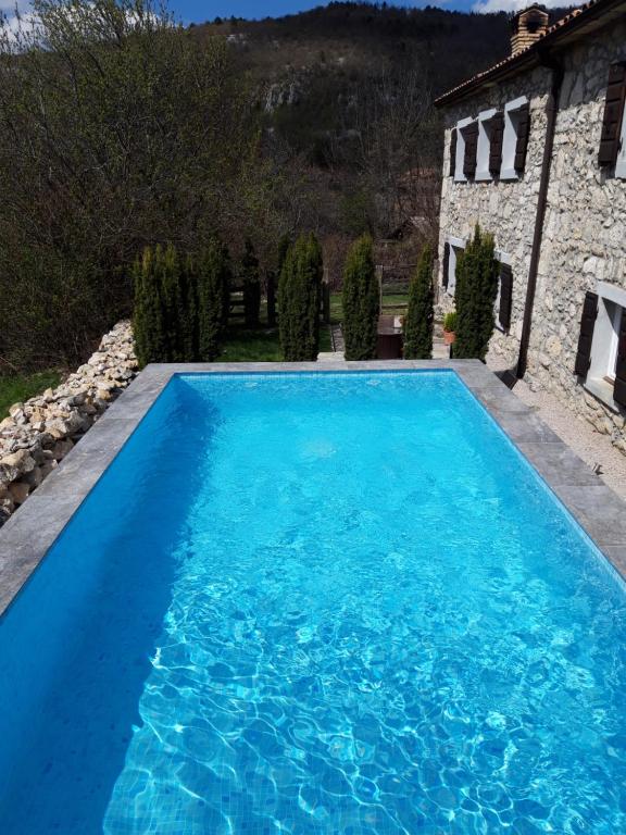 a large blue swimming pool in front of a house at Apartments Casa Nora in Lupoglav