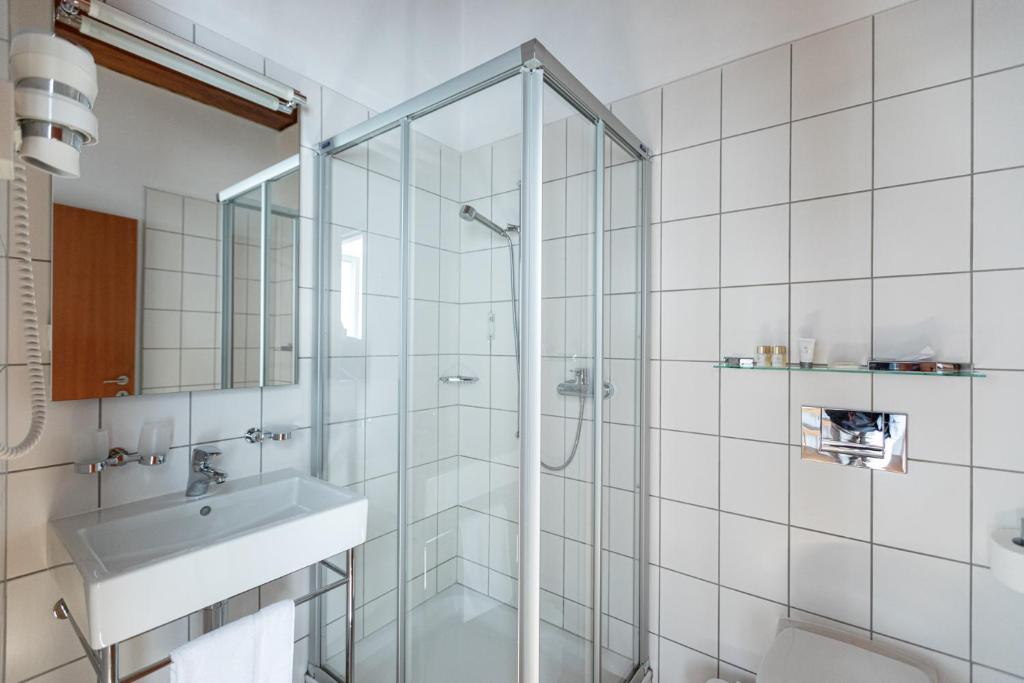 a bathroom with a glass shower and a sink at Hotel Restaurant Stockalperturm in Ruden
