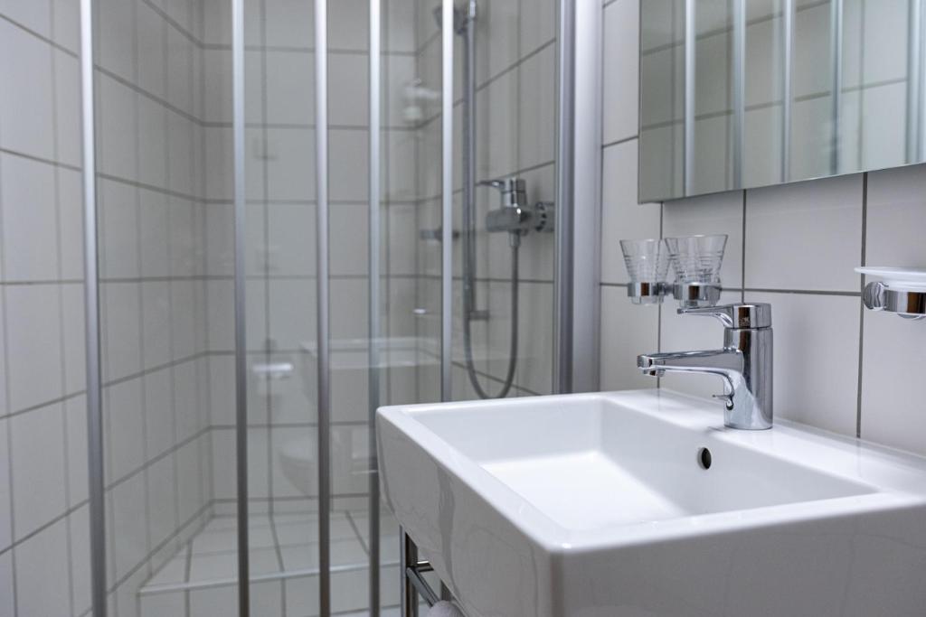 a white bathroom with a sink and a shower at Hotel Restaurant Stockalperturm in Ruden