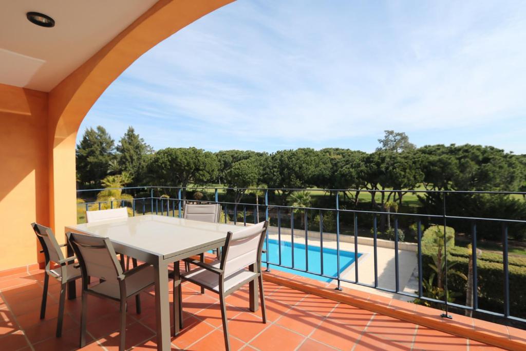 einen Balkon mit einem Tisch, Stühlen und einem Pool in der Unterkunft AL - Apartamento Vila Sol F5 T in Quarteira