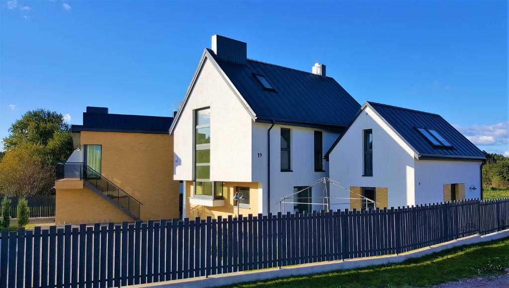 a house with a black roof behind a fence at Smėlio Vila Apartments in Palanga