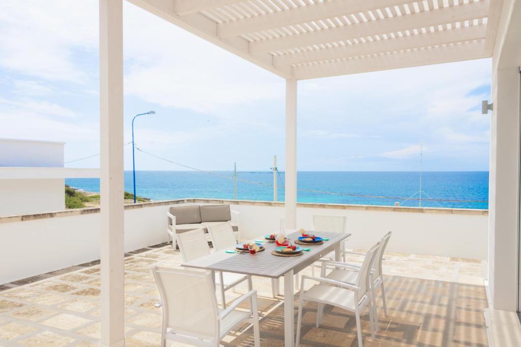 una mesa y sillas en un balcón con vistas al océano en Suite Jonica, en Torre Suda