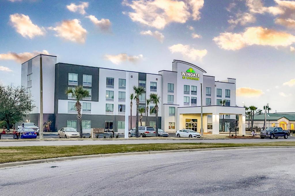 a large white building with cars parked in a parking lot at Wingate by Wyndham Panama City Area Lynn Haven in Panama City