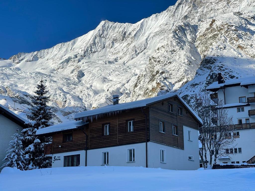 a building in the snow in front of a mountain at Chalet Casa Sharm in Saas-Fee