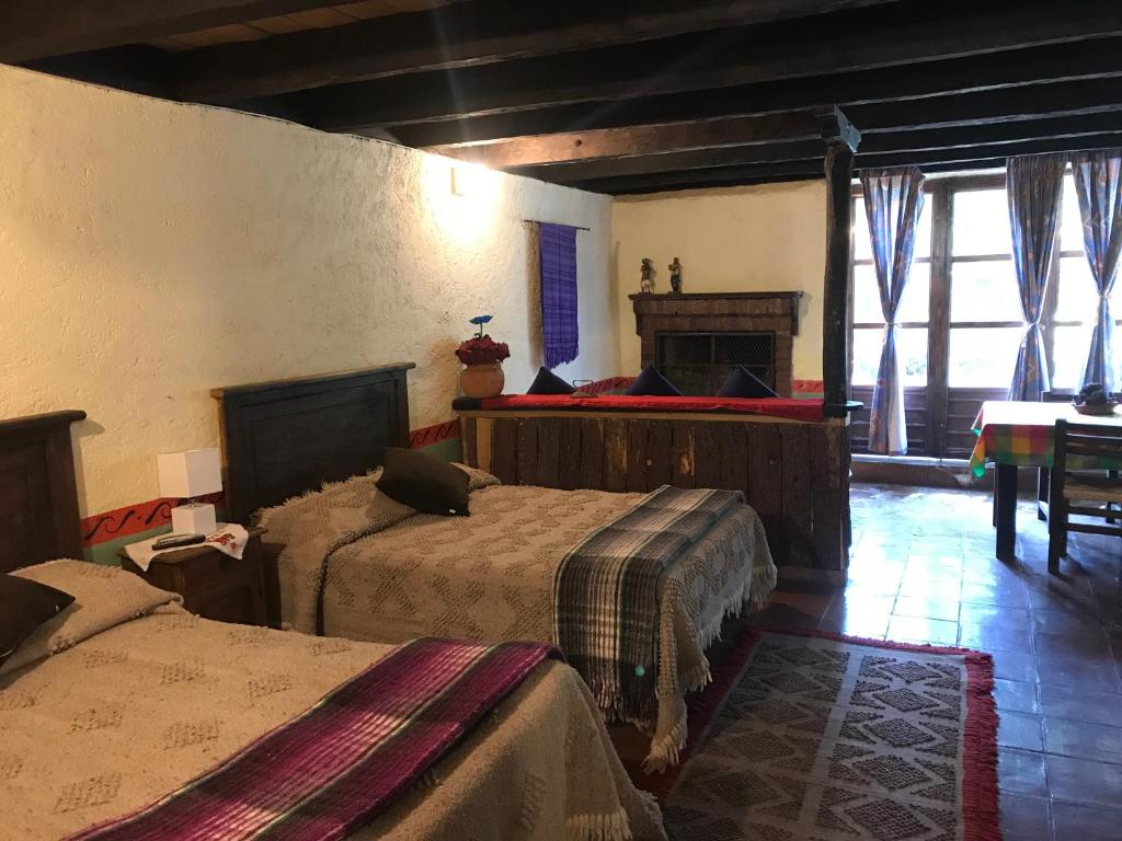 a bedroom with two beds in a room with windows at Rancho Cumbre Monarca in La Ciénega