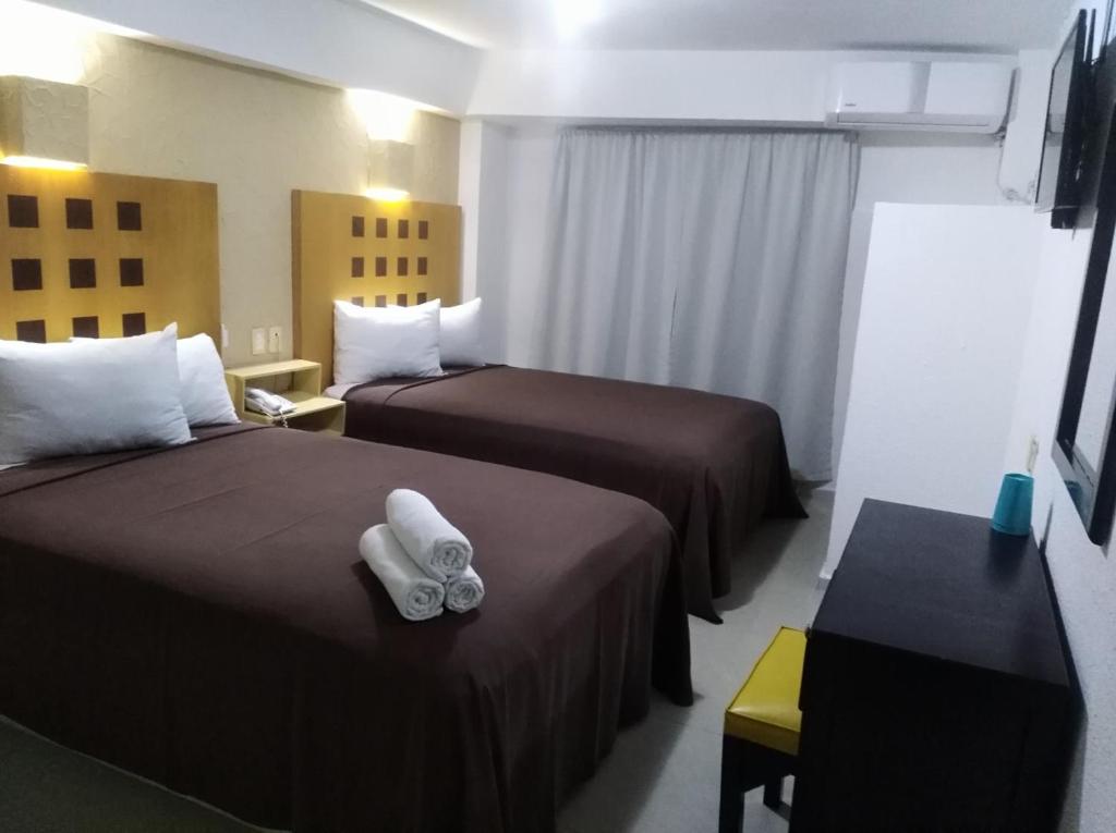 a hotel room with two beds with towels on them at Hotel Posada del Carmen in Veracruz