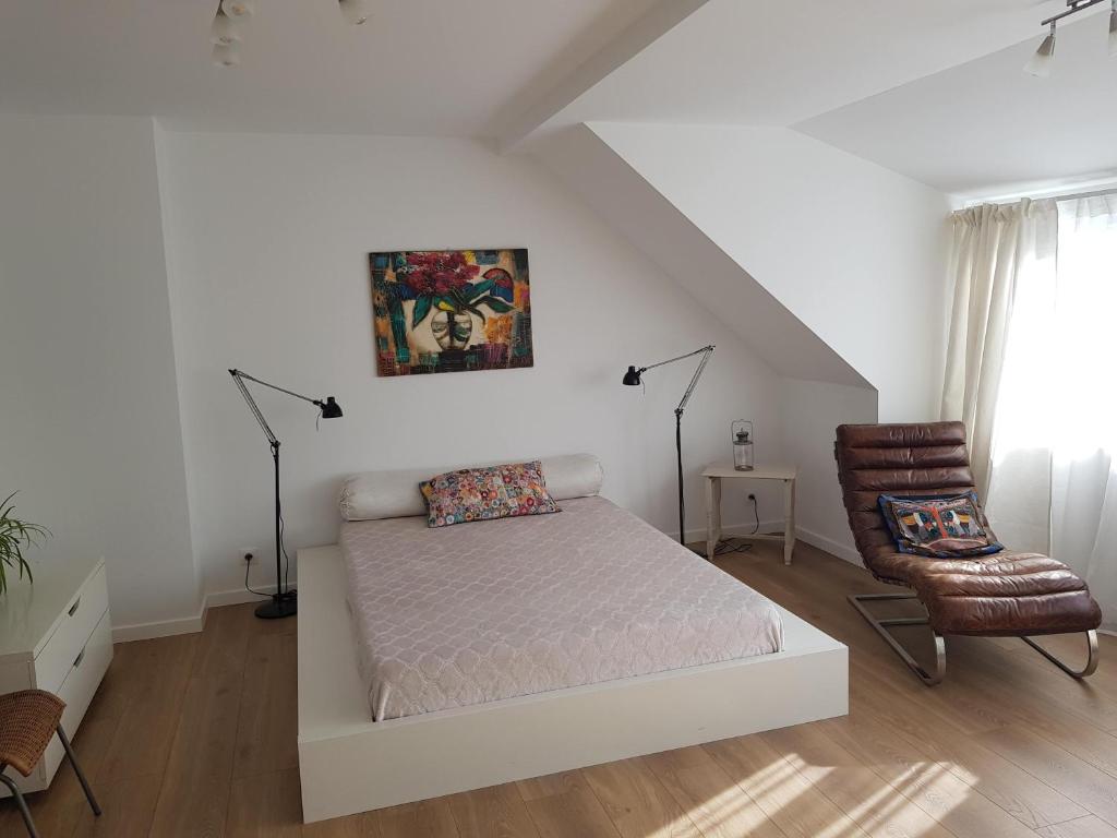 um quarto branco com uma cama e uma cadeira em MAISON DES FLEURS em Bruxelas