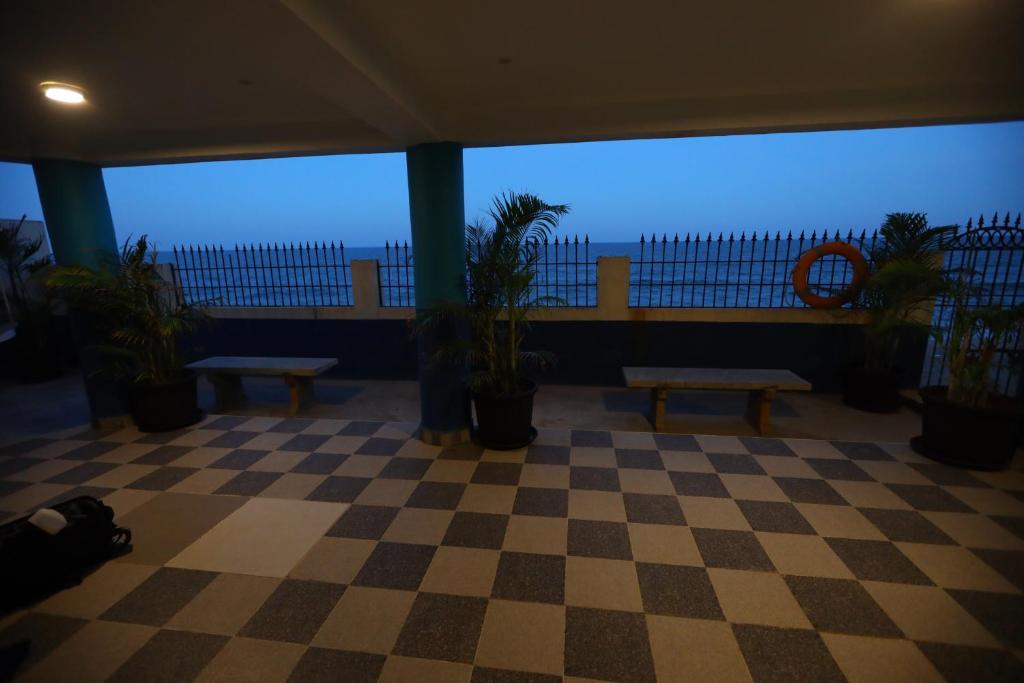 a room with a checkered floor with benches and plants at Lamel Cove Beach Resort in Puducherry