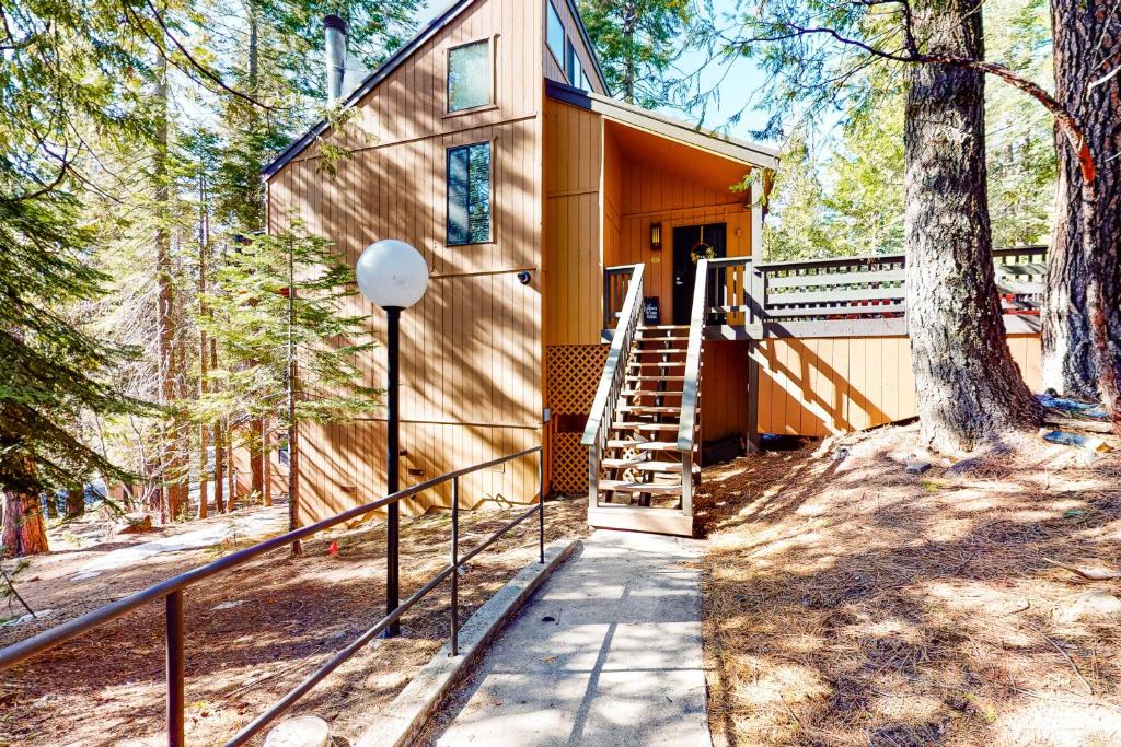 a cabin in the woods with a staircase leading to the door at The Sleepy Hollow in Shaver Lake