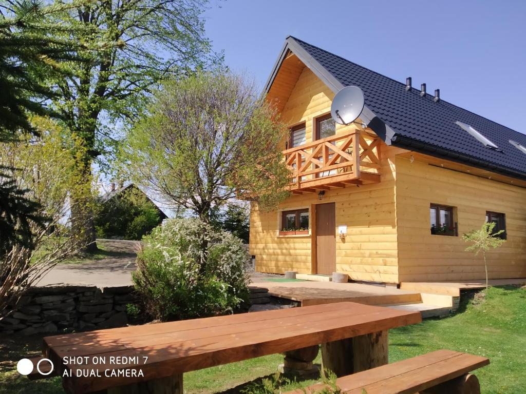 a wooden house with a bench in front of it at Apartamenty Pod Lipą in Lutowiska