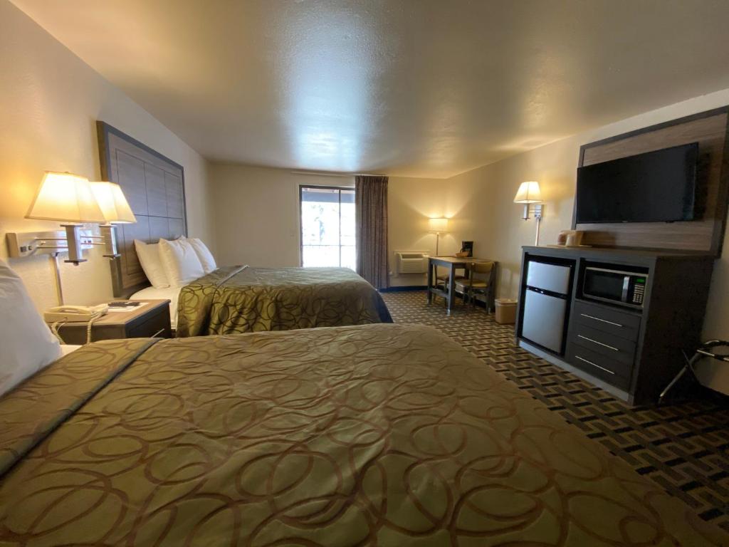 a hotel room with two beds and a flat screen tv at Motel In The Pines in Munds Park
