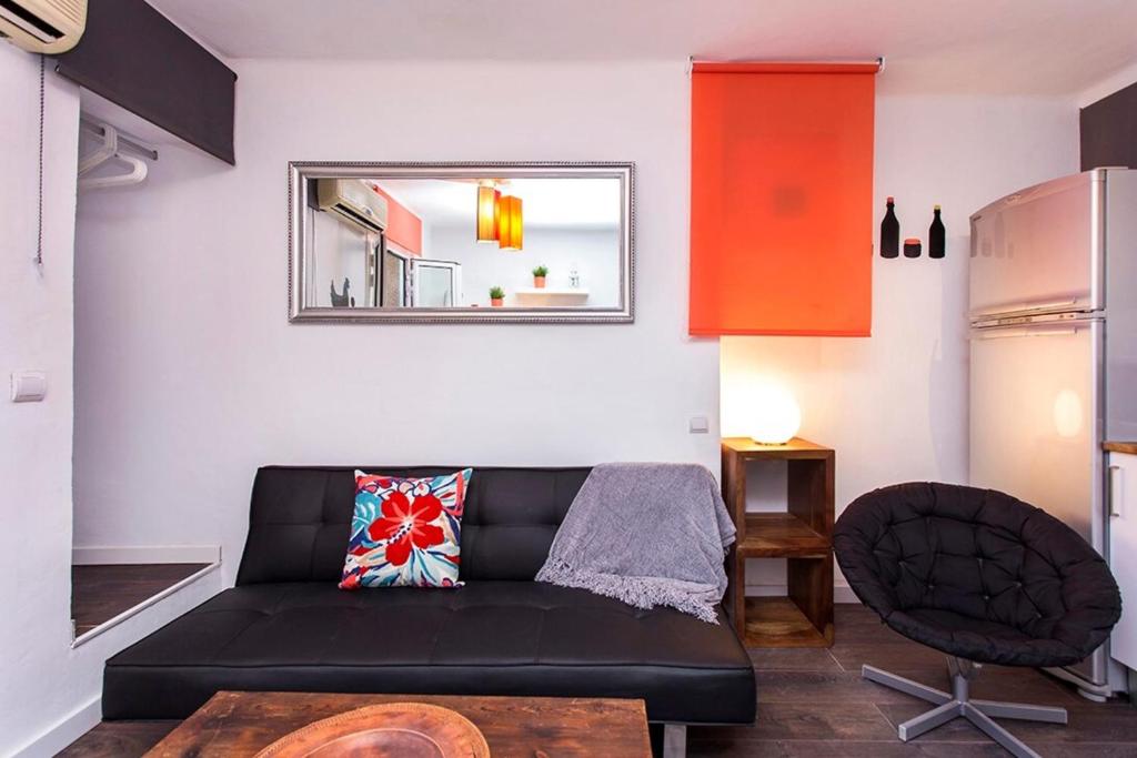 a living room with a black couch and a chair at Pleasant Studio with Balcony Close to Camp Nou in Hospitalet de Llobregat