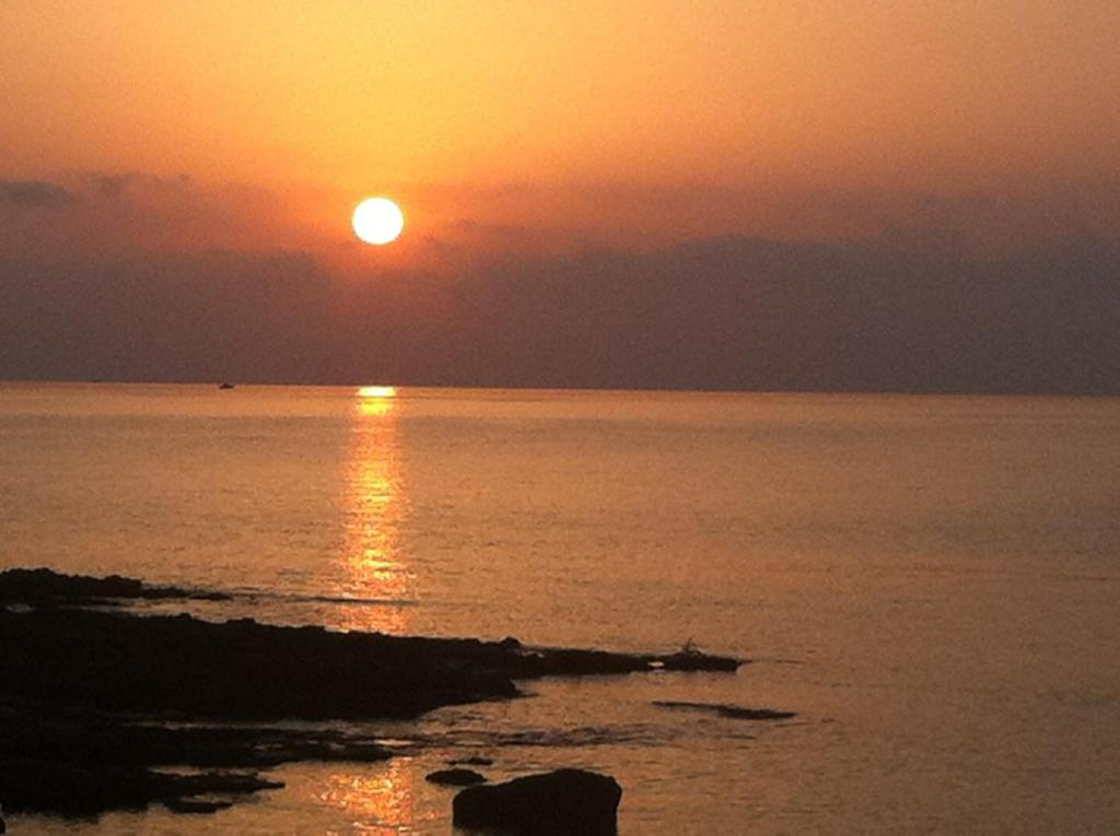 una puesta de sol sobre el océano con la puesta de sol en san lorenzo a 4 mt dal mare colore smeraldo a due passi da Marzamemi, en Reitani