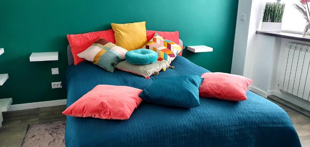 a blue bed with colorful pillows on top of it at Nordapartament in Suceava