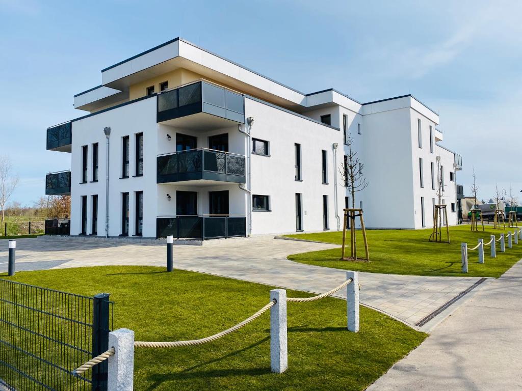 un grand bâtiment blanc avec une clôture devant lui dans l'établissement Haus Meerruhe Karlshagen Apartment 1-6, à Karlshagen