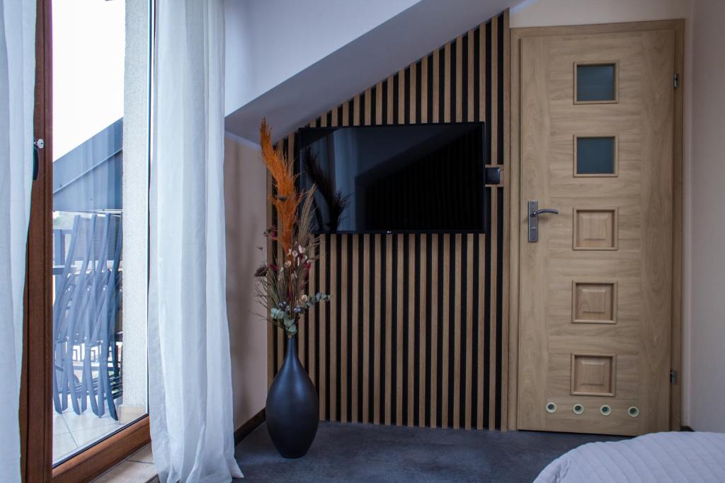 a vase with flowers in front of a door with a television at ZOFIA in Władysławowo