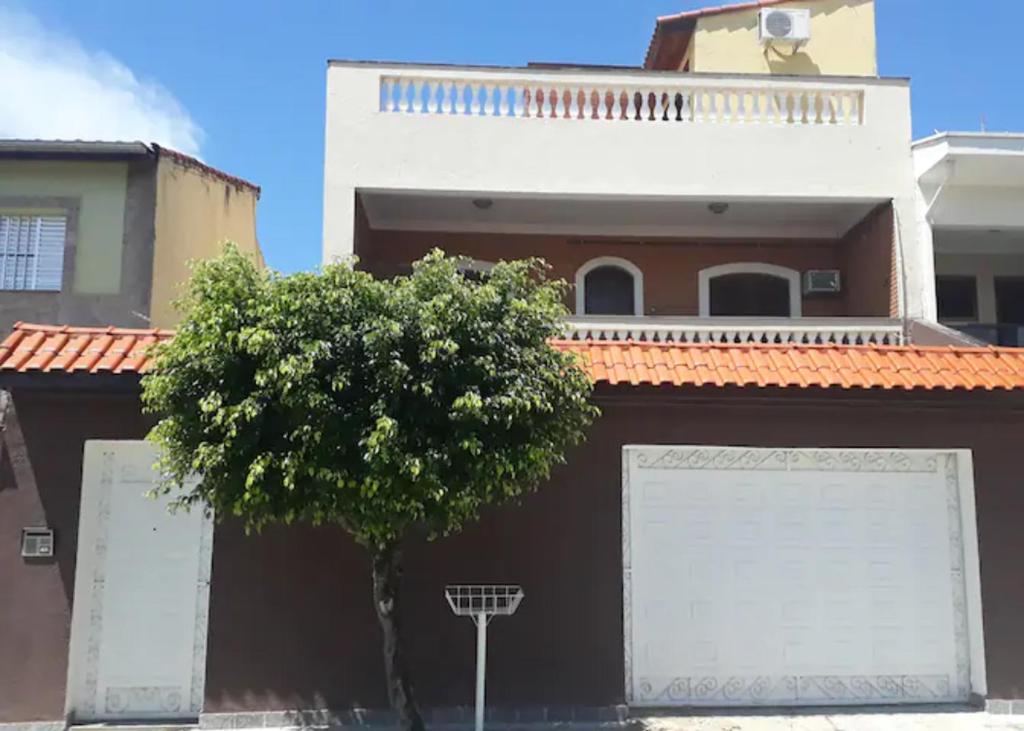 a building with two garage doors and a tree at Casa com 6 quartos e confortável próxima ao Santuário in Aparecida