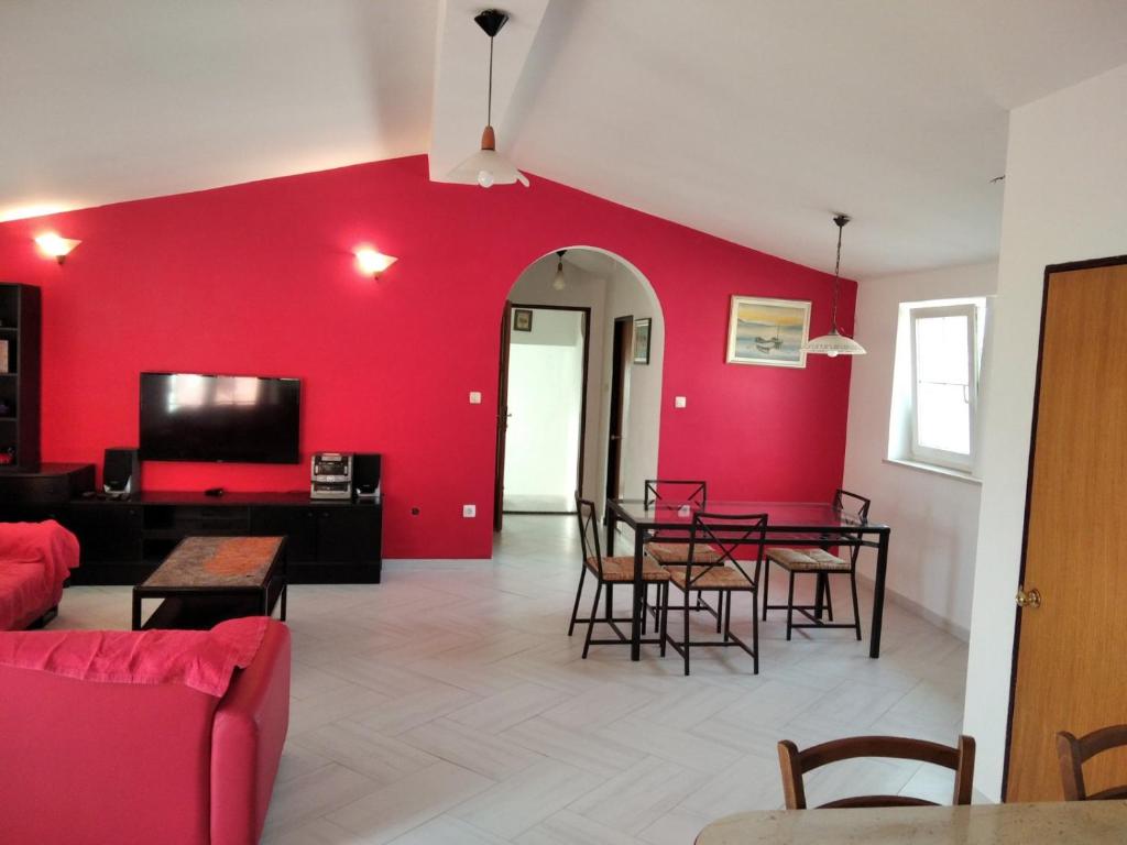 ein Wohnzimmer mit roten Wänden, einem Tisch und Stühlen in der Unterkunft Gecko Apartment in Rijeka