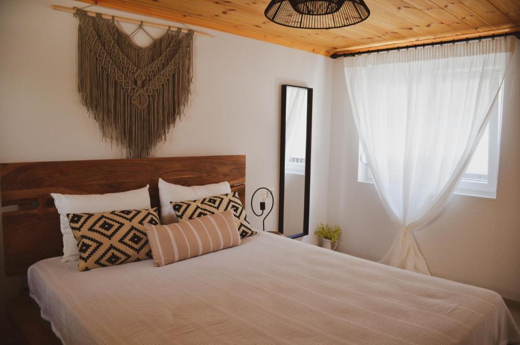 um quarto com uma cama com almofadas e uma janela em Samothrakis Michelangelo 101 Luxury apartment em Samotrácia