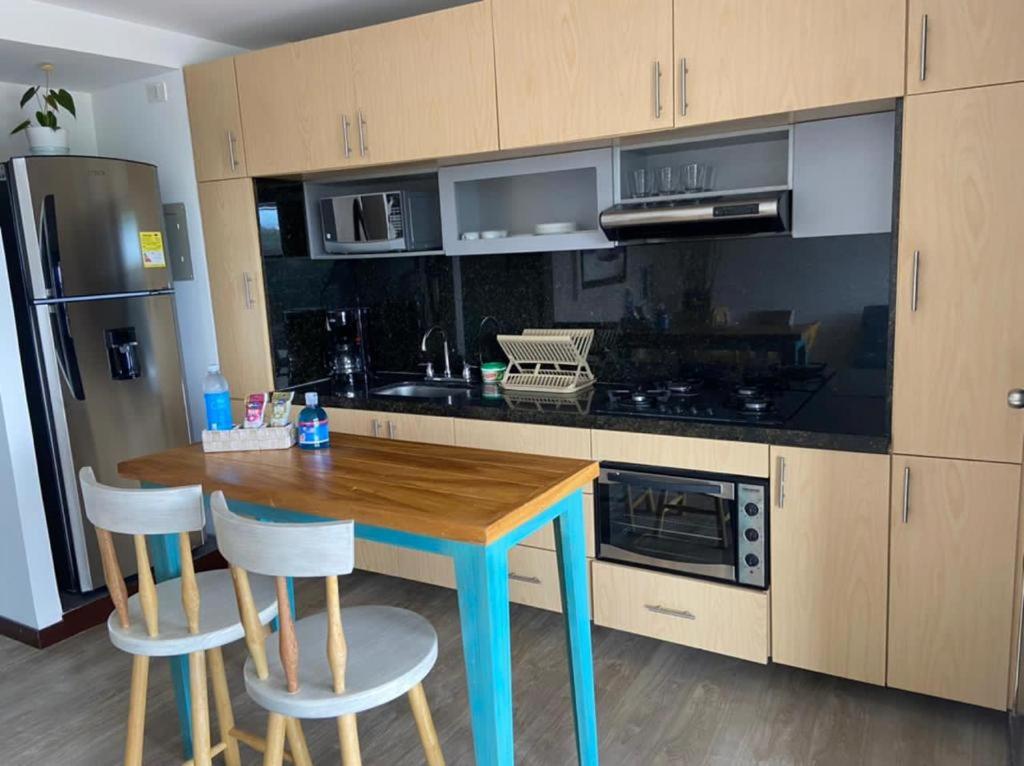 a kitchen with a wooden table and two stools at Apto 307 Metroloft Armenia in Armenia