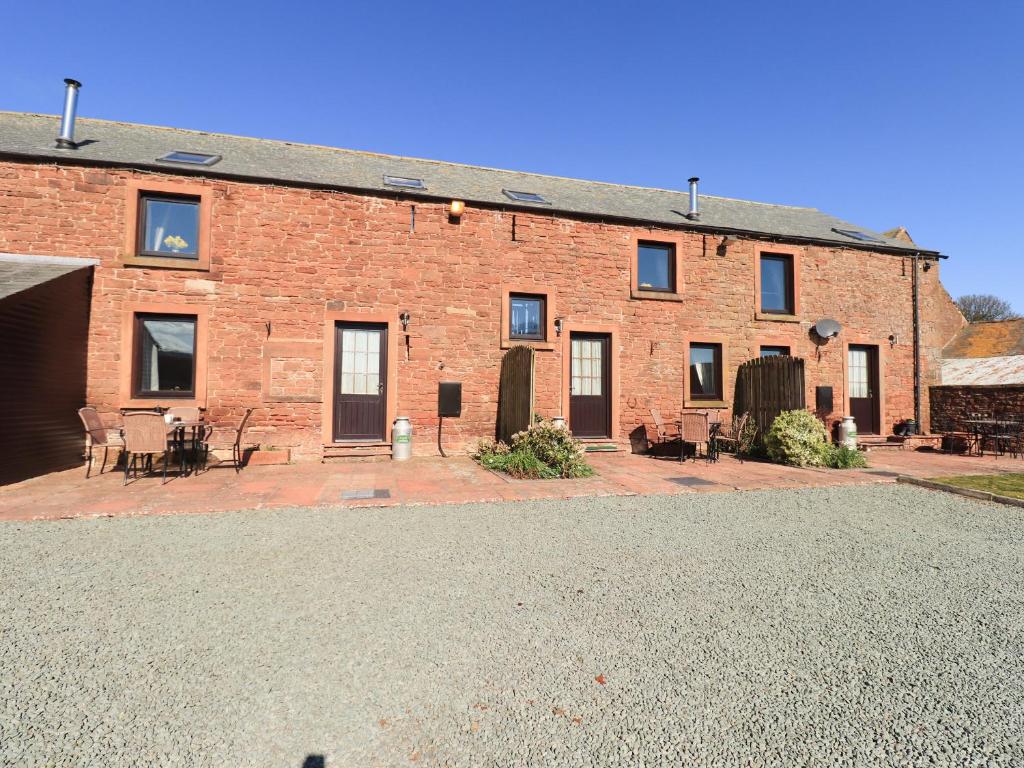 a large brick building with a patio in front of it at Hayloft Cottage in Wigton