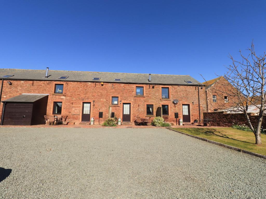 a large brick building with a driveway in front of it at Horseshoe Cottage in Wigton