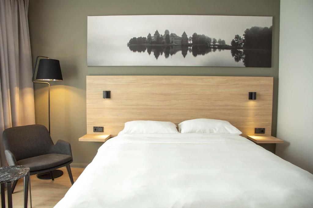 a bedroom with a large white bed and a chair at Park Inn by Radisson Vilnius Airport Hotel & Conference Centre in Vilnius