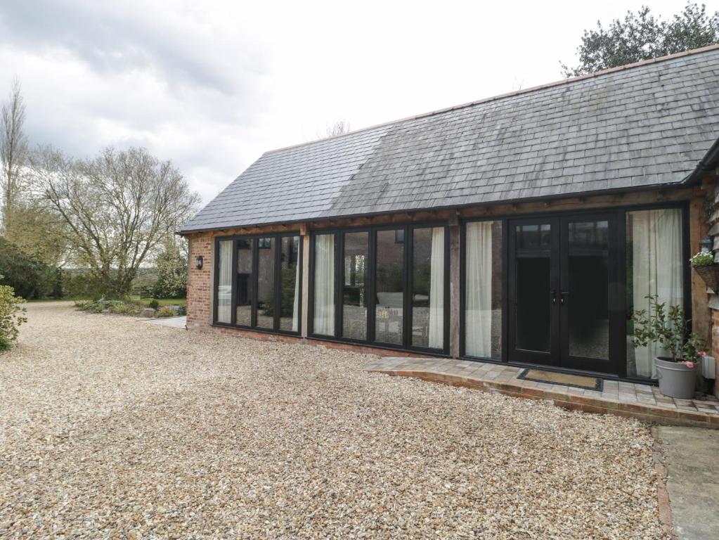 a barn conversion with black windows and a gravel driveway at The Courtyard - Hilltop Barn in Blandford Forum