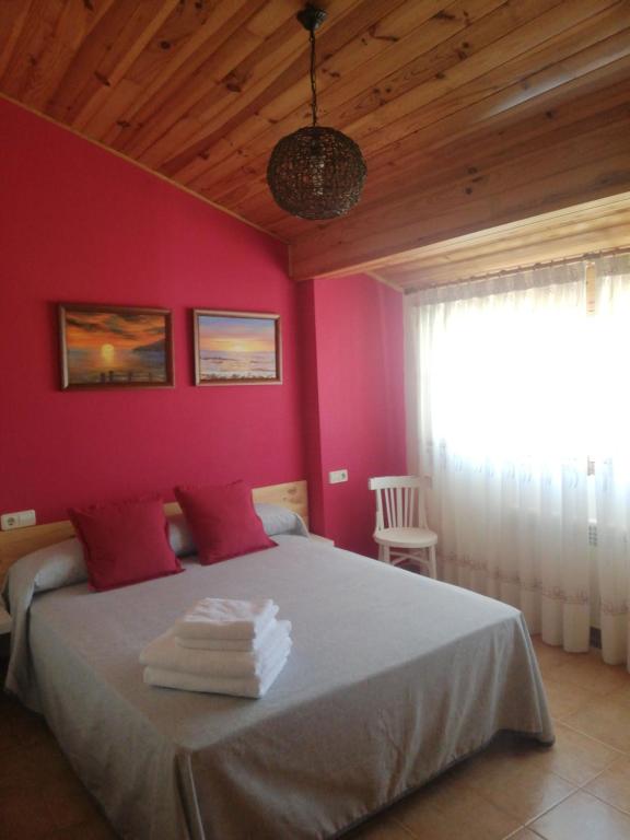 Casa Rural Los Pineros في Montán: غرفة نوم بسرير كبير بجدران وردية