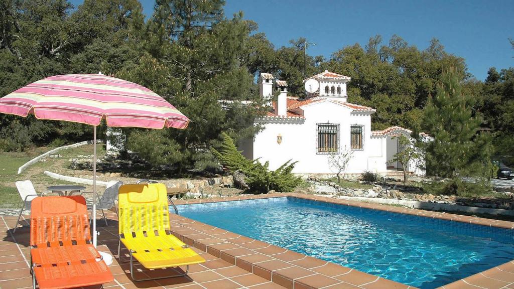 een zwembad met 2 stoelen en een parasol bij Granada 003 in Alhama de Granada