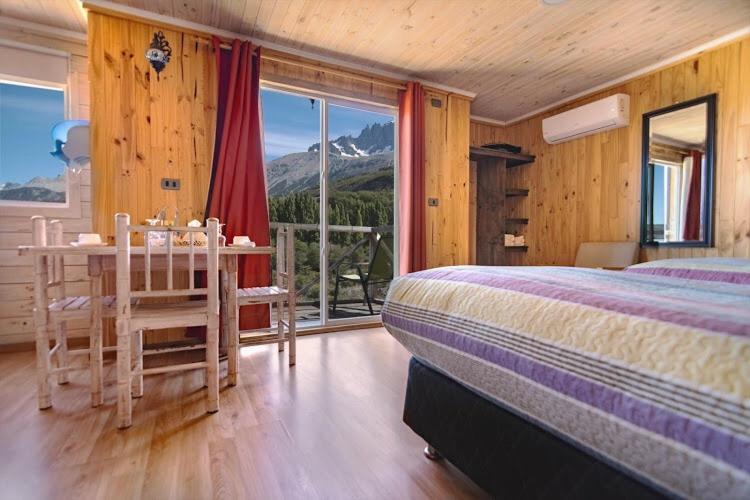 a bedroom with a bed and a table and a window at B&B y Cabañas Cerro Castillo in Villa Cerro Castillo