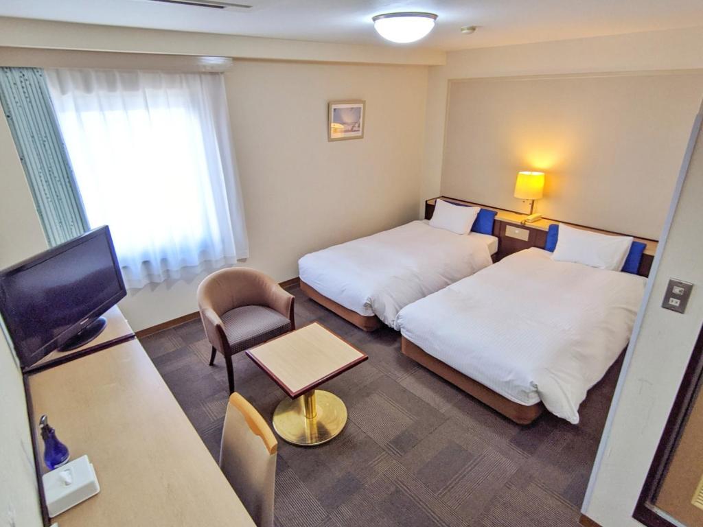 a hotel room with two beds and a television at Kadoma Public Hotel/ Vacation STAY 33577 in Kadoma