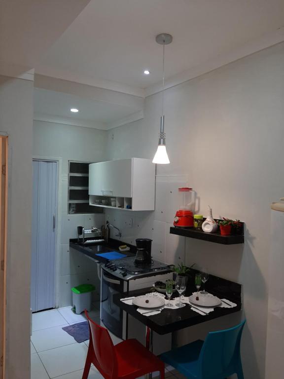 cocina con mesa y 2 sillas rojas en Aconchego e requinte flat Praia atalaia, en Aracaju
