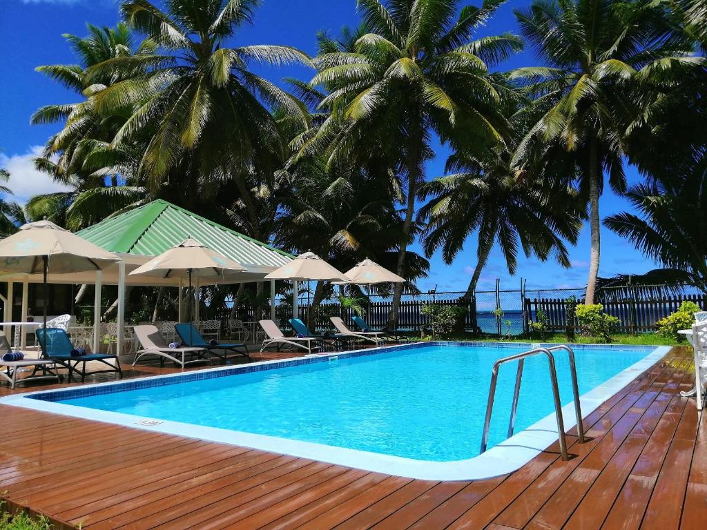 uma piscina com um deque de madeira e palmeiras em Le Relax Beach Resort em Grand'Anse Praslin