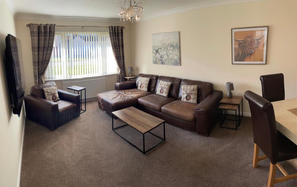 uma sala de estar com um sofá de couro castanho e cadeiras em Holm from Home em Inverness