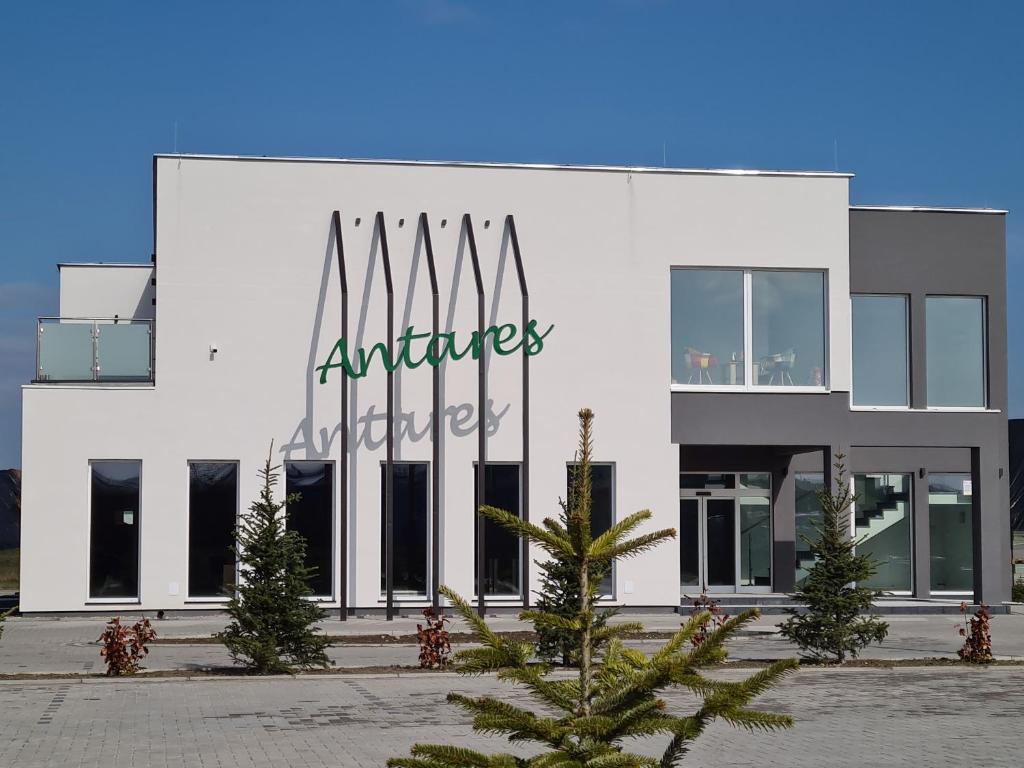 un edificio blanco con un cartel. en Hotel ANTARES, en Sępólno Krajeńskie
