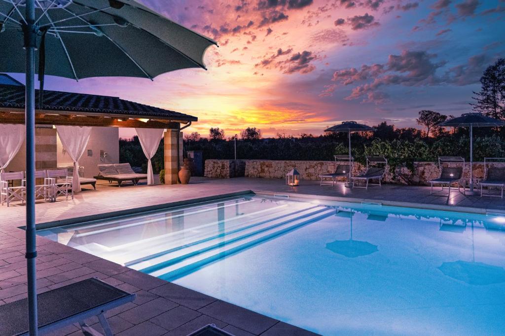 a swimming pool with a sunset in the background at Masseria Tenuta Flora Maria in Leverano