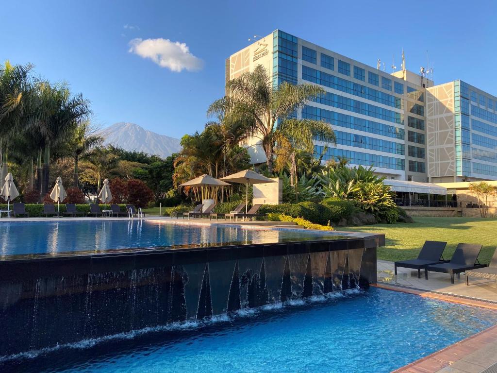 a swimming pool with a fountain in front of a building at Mount Meru Hotel in Arusha