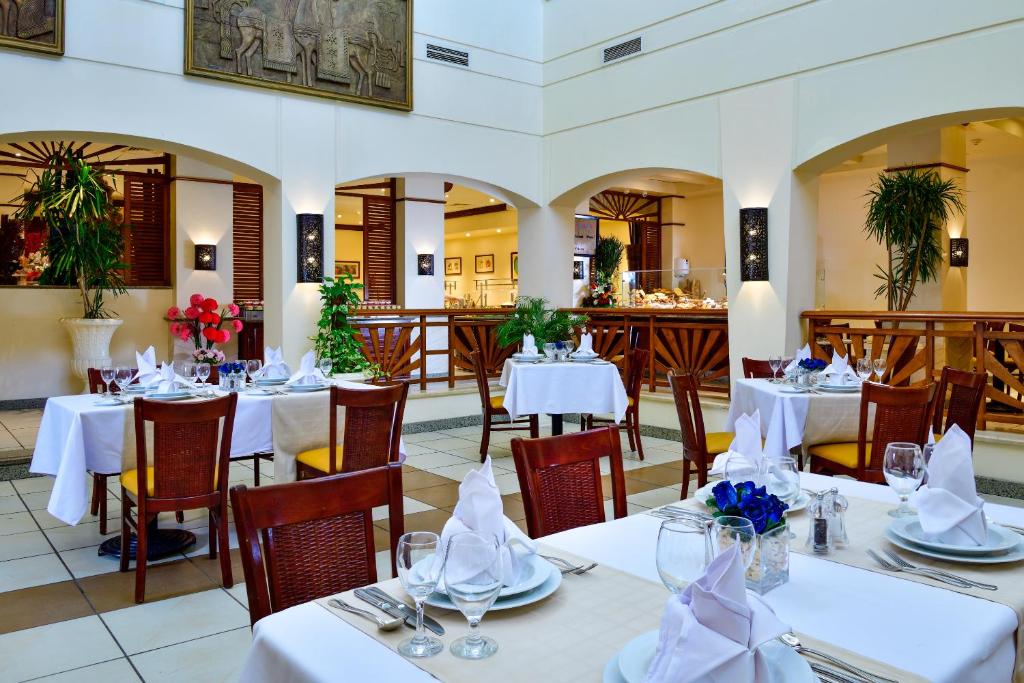 a restaurant with tables and chairs with white tablecloths at Sharm Grand Plaza Resort - Families and Couples Only in Sharm El Sheikh