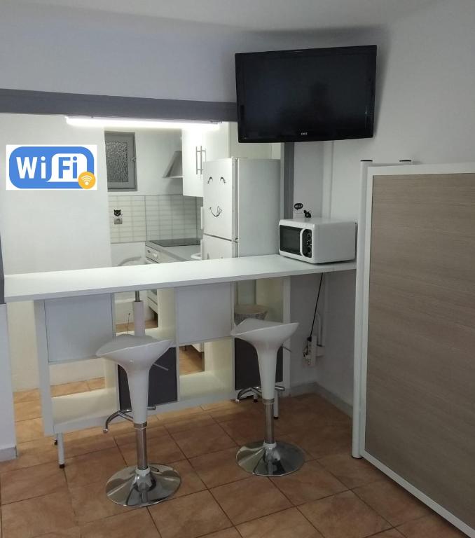 a kitchen with a white counter with a microwave and stools at R&G SALOU CENTER in Salou