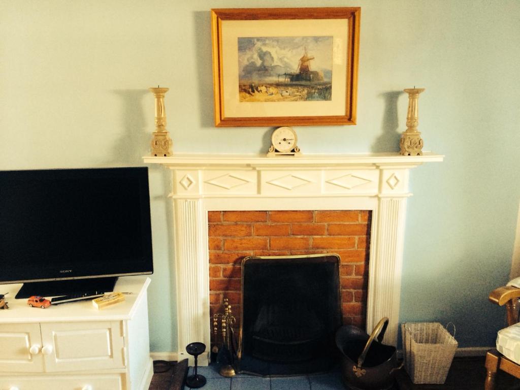 a living room with a fireplace and a tv at 2 bedroomed fisherman’s cottage near quay in Blakeney